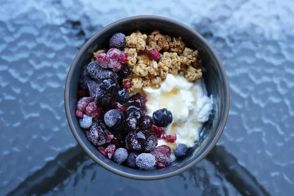 A yogurt bowl with frozen berries and granola